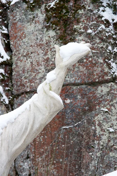 A statue hand full of snow with natural rock as background — Stock Photo, Image
