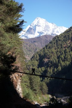 Porter crossing rope bridge at Everest trail in Himalaya, Nepal clipart