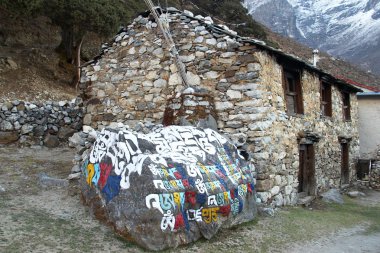 Nepal 'deki Himalayalar' daki eski Nepal evinin yakınlarındaki Budist manikür taşı.