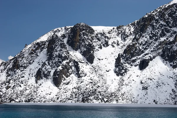 Rotsachtige oever van het meer bedekt met sneeuw, Himalaya, Nepal — Stockfoto