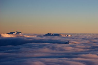 Mountains above the clouds at sunset clipart