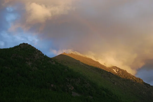 Berg, solnedgång och regnbåge — Stockfoto