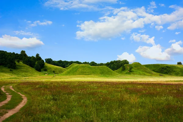 Холмы, зеленая трава, голубое небо, весна — стоковое фото