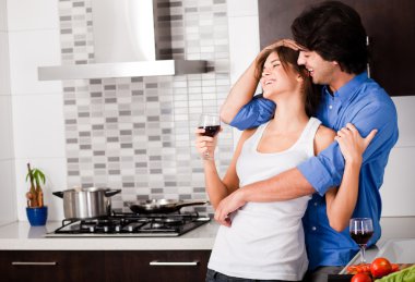 Young couple hug in their kitchen clipart