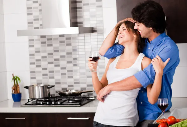 Jovem casal abraço em sua cozinha — Fotografia de Stock