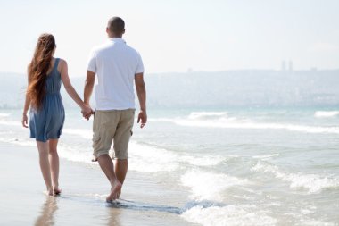 Young couple walk at the beach clipart