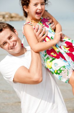 Kid and father playing in the beach clipart