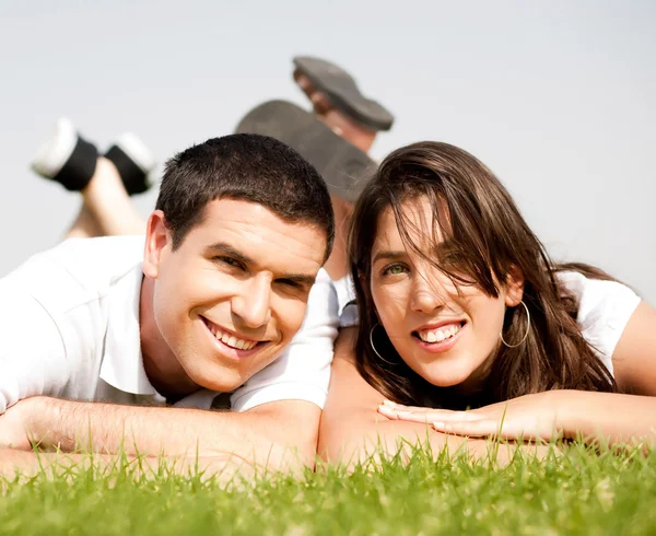 Счастливая молодая пара ложится на траву — стоковое фото