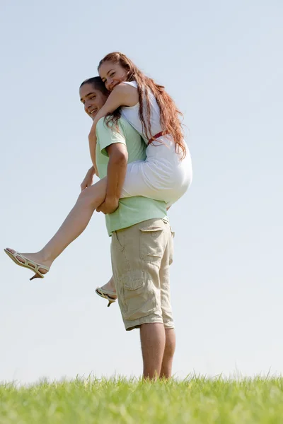 Jovem homem piggybacking seu namorada — Fotografia de Stock
