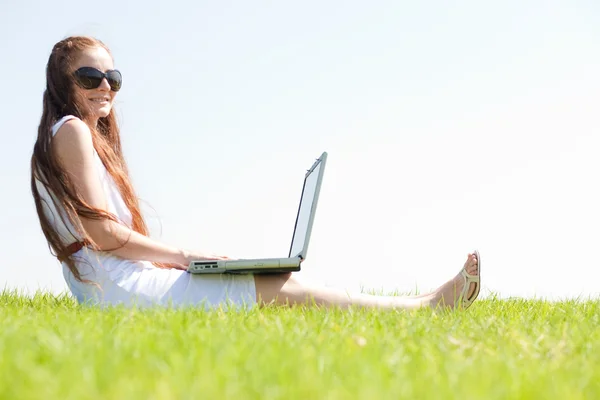 Μια νεαρή γυναίκα σε πάρκο χρησιμοποιώντας φορητό υπολογιστή — Φωτογραφία Αρχείου