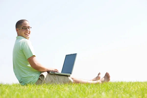 Egy fiatal férfi a park használ laptop — Stock Fotó