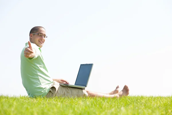 Un jeune homme sur le parc en utilisant un ordinateur portable — Photo