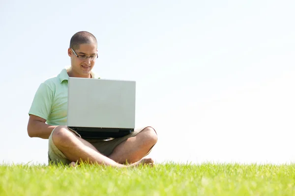 Молодой человек в парке с ноутбуком — стоковое фото