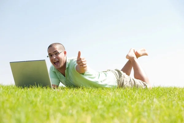 Un jeune homme sur le parc en utilisant un ordinateur portable — Photo