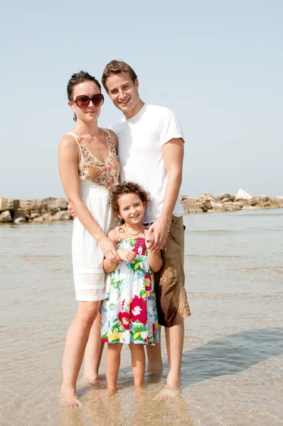 Junge Familie steht mit Kind am Strand — Stockfoto