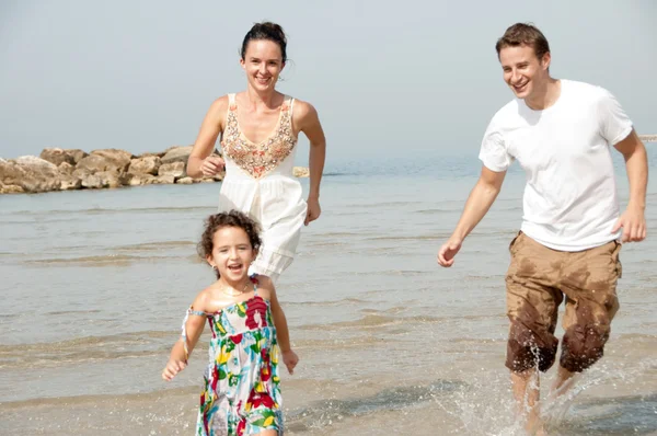 Kind spielt mit Eltern am Strand — Stockfoto