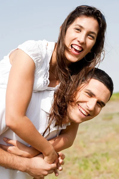 Genç çift piggybacking gülümseyen — Stok fotoğraf