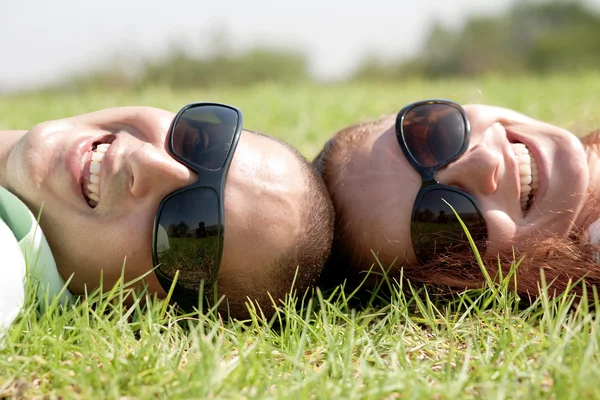 Glückliches junges Paar lächelt auf dem Rasen — Stockfoto