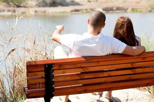 Молодая пара, сидящая на деревянной скамейке — стоковое фото