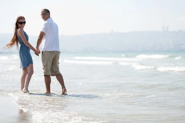 Веселая пара, гуляющая на пляже — стоковое фото