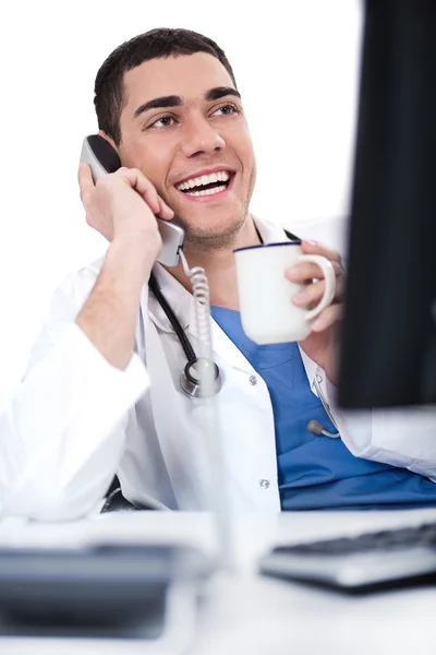 Χαμογελαστός νεαρός γιατρός πάνω από το τηλέφωνο — Φωτογραφία Αρχείου