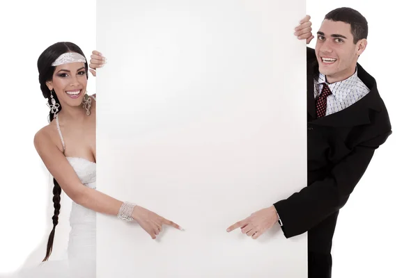 Bruid en bruidegom wijzend op leeg bord — Stockfoto