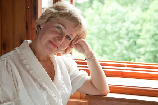 The mature woman at the open window — Stock Photo, Image