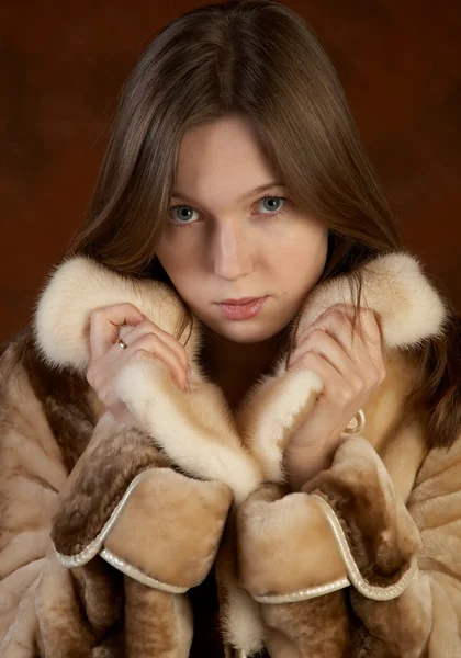 A menina em um casaco de peles em motley backgro — Fotografia de Stock
