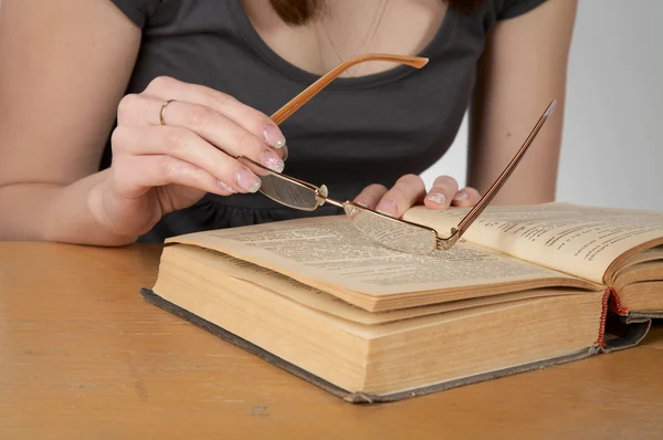 stock image The girl holds glasses and reads the boo