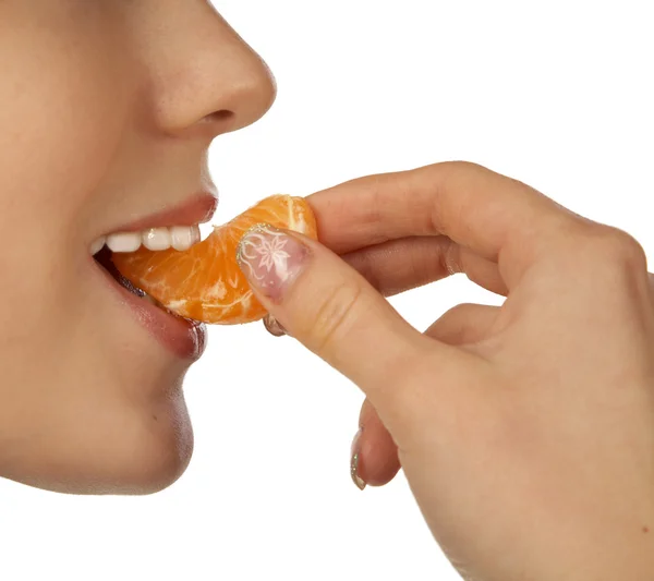 Das Mädchen beißt in ein Stück Mandarine — Stockfoto
