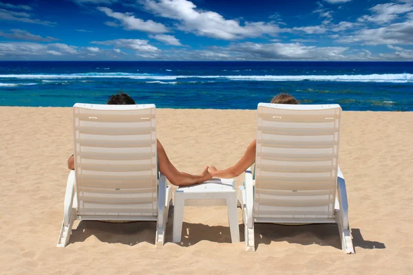 Ζευγάρι στην παραλία καρέκλες, κρατώντας τα χέρια νέα — Φωτογραφία Αρχείου