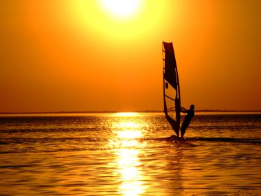 Silhouette of a windsurfer on waves of a clipart