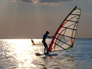 A women is learning windsurfing at the s clipart