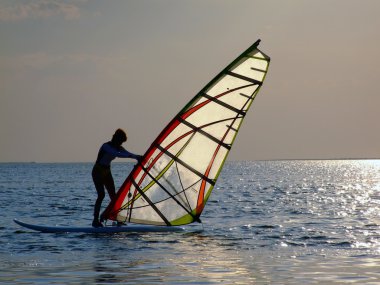 A women is learning windsurfing at the s clipart