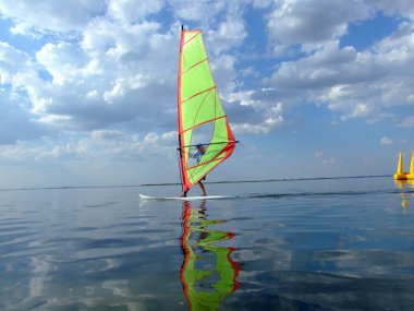 Windsurfer and its reflection in water o clipart
