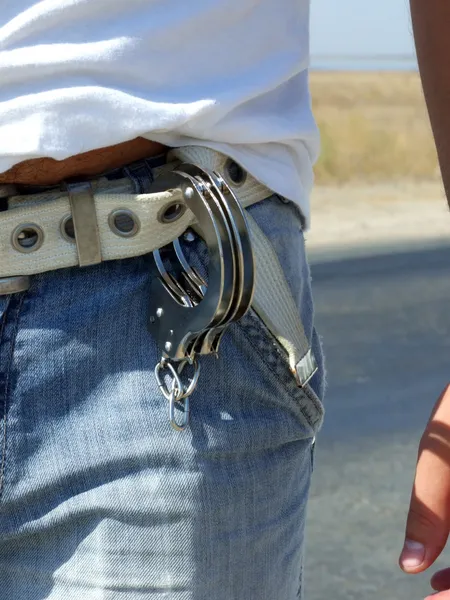 Las esposas colgando de un cinturón de jeans — Foto de Stock