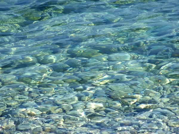 Guijarros bajo una superficie azul de mar wate —  Fotos de Stock
