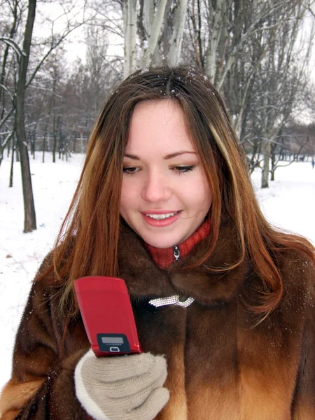Flickan på vintern i park med phon — Stockfoto