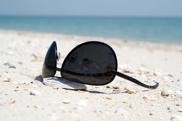 The black sunglasses lying on a beach — Stock Photo, Image