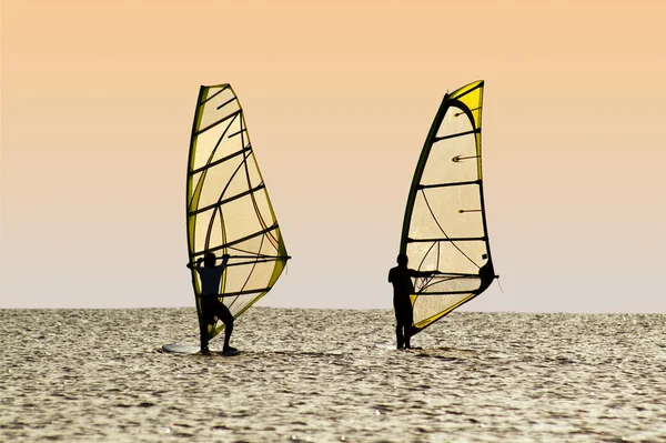 Siluetas de dos windsurfistas sobre olas — Foto de Stock