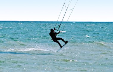 Silhouette of a kitesurfer on waves of a clipart
