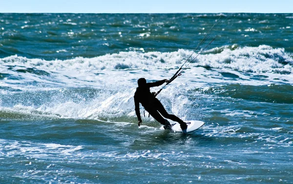Silhouette di un kitesurfer su onde di un — Foto Stock