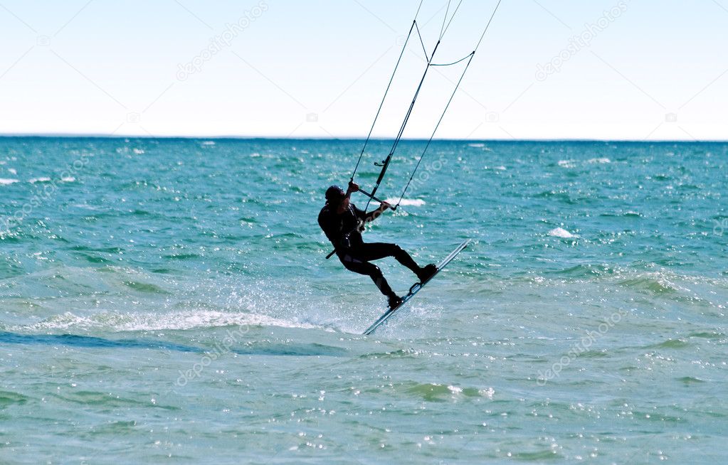Silhouette of a kitesurfer on waves of a