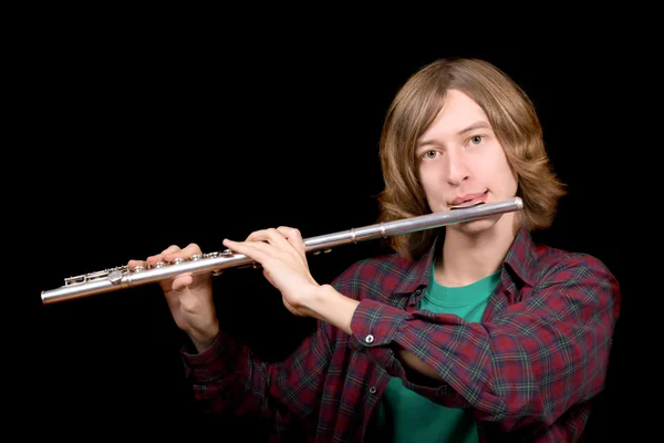 O jovem toca flauta sobre preto — Fotografia de Stock