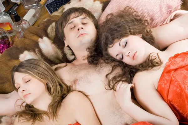 Schlafender junger Mann und zwei Frauen nach einem — Stockfoto
