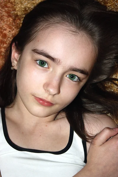 Mädchen liegt mit grünen Augen auf einem Teppich — Stockfoto