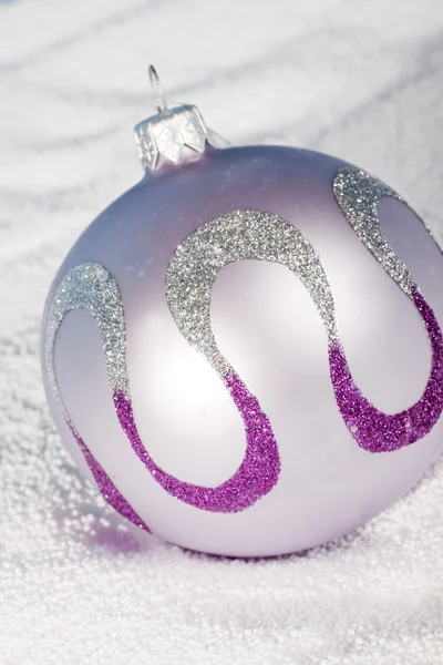 Tender lilac Christmas bauble on to snow — Stock Photo, Image