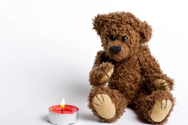 Toy bear Teddy and burning candle. — Stock Photo, Image