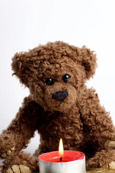 Toy bear Teddy and burning candle. — Stock Photo, Image