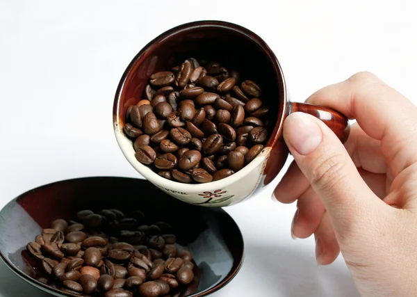 Kopp med kaffebönor vände av en hand. — Stockfoto